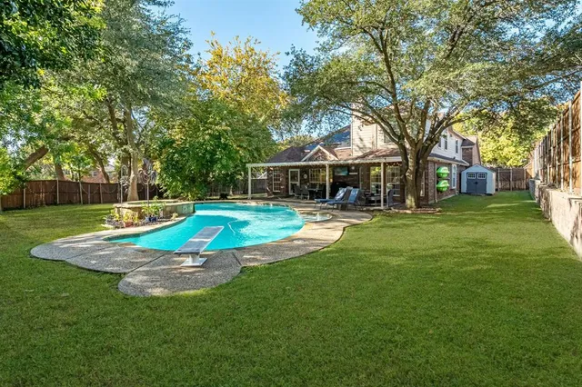 a view of a house with a big yard potted plants and large tree
