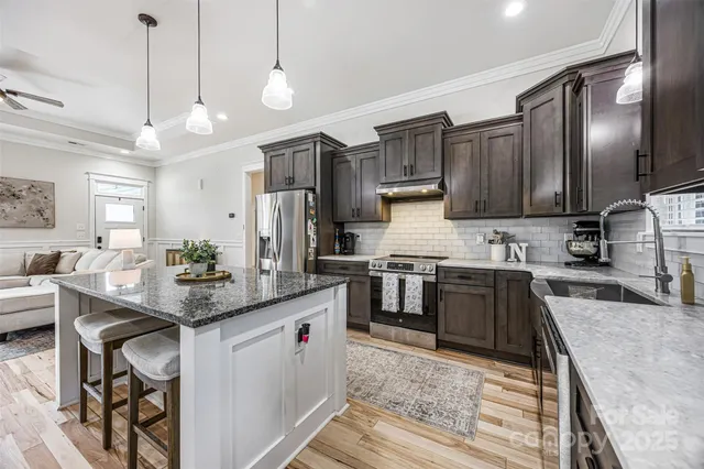 a kitchen with stainless steel appliances kitchen island granite countertop a sink stove and cabinets