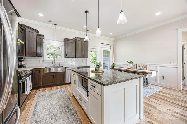 a kitchen with stainless steel appliances granite countertop a sink a stove and a refrigerator