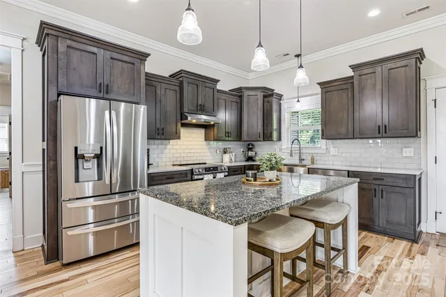 a kitchen with granite countertop a refrigerator stove microwave and cabinets