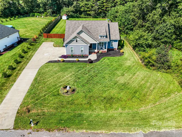 a aerial view of a house with a big yard potted plants and large tree