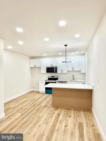 a view of kitchen with kitchen island a sink wooden floor and living room view