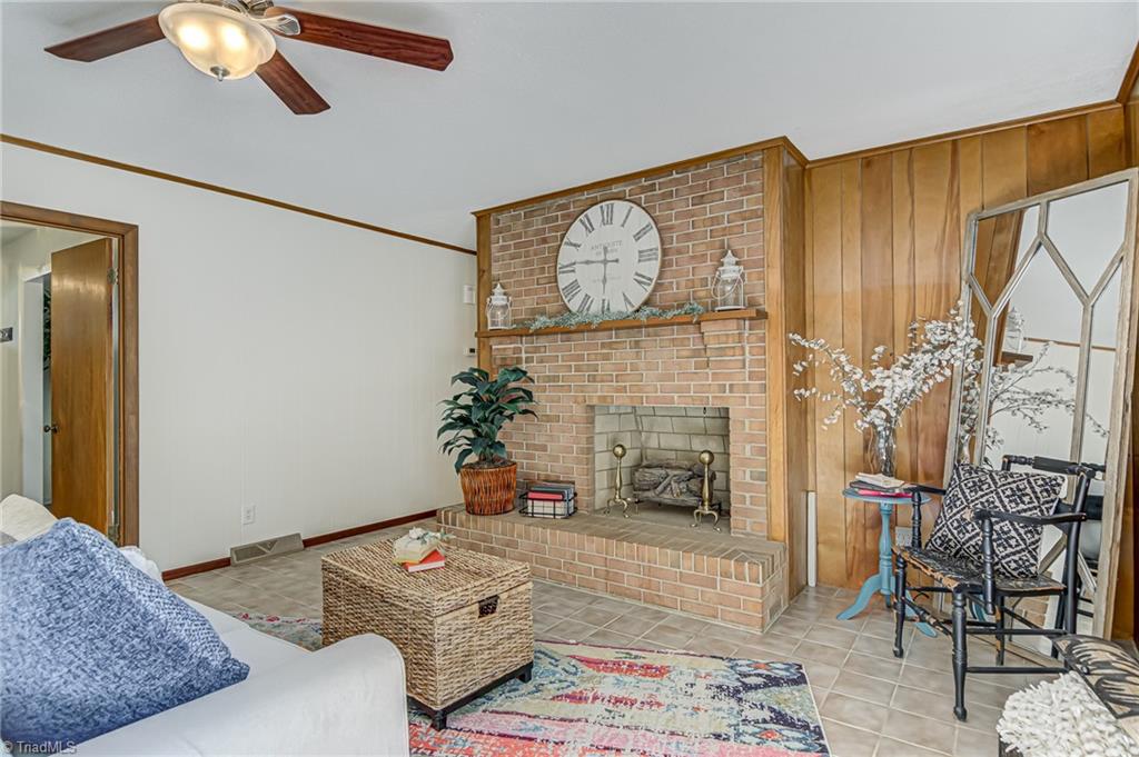 2606 Maxine Drive High Point, NC 27265 - Photo 5 of 34 Den features ceiling fan, fireplace, tile flooring, and wood accent walls.