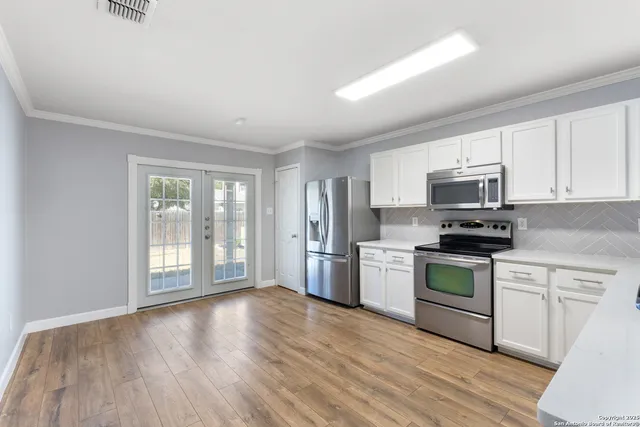 a kitchen with granite countertop white cabinets and stainless steel appliances