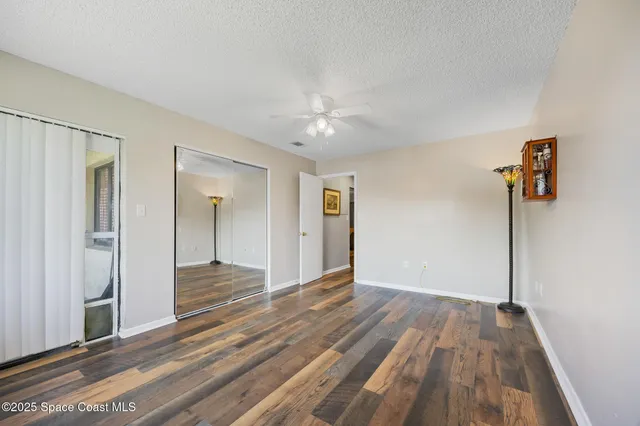a view of a room with wooden floor and a ceiling fan