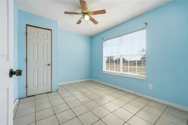 a view of an empty room with wooden floor and a ceiling fan