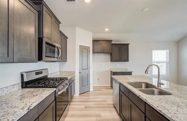 a kitchen with stainless steel appliances granite countertop a sink stove microwave and refrigerator