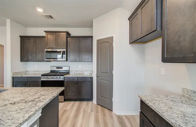 a kitchen with kitchen island granite countertop stainless steel appliances and sink