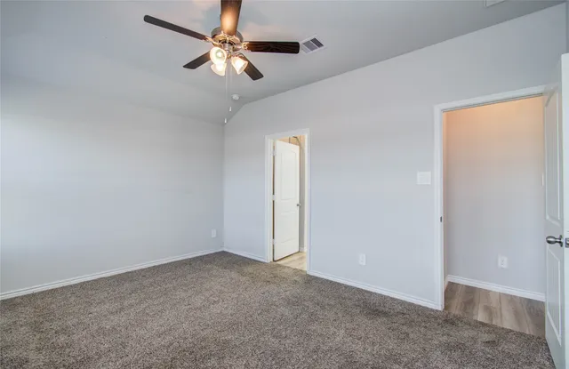 an empty room with a chandelier fan and windows