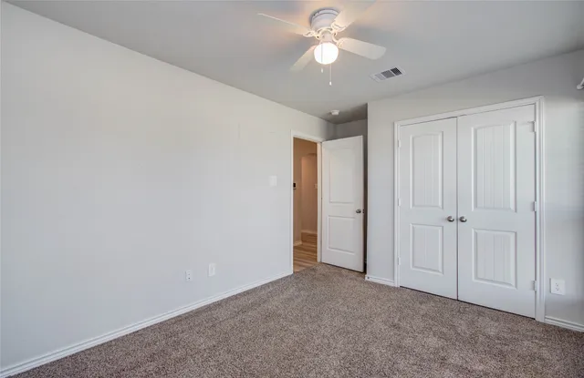 an empty room with a ceiling fan and a window