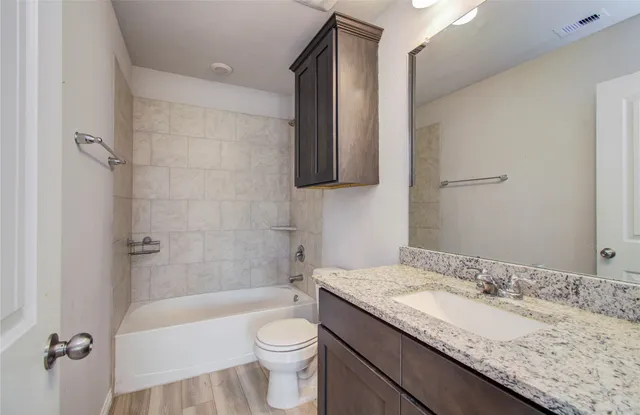 a bathroom with a granite countertop sink a toilet and bathtub