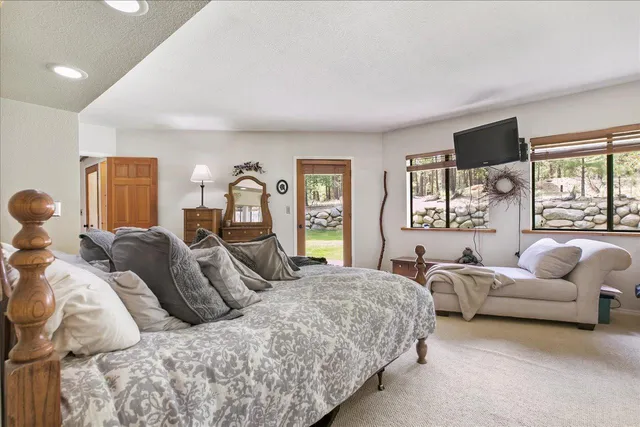 a bedroom with a bed couches chair and a large window