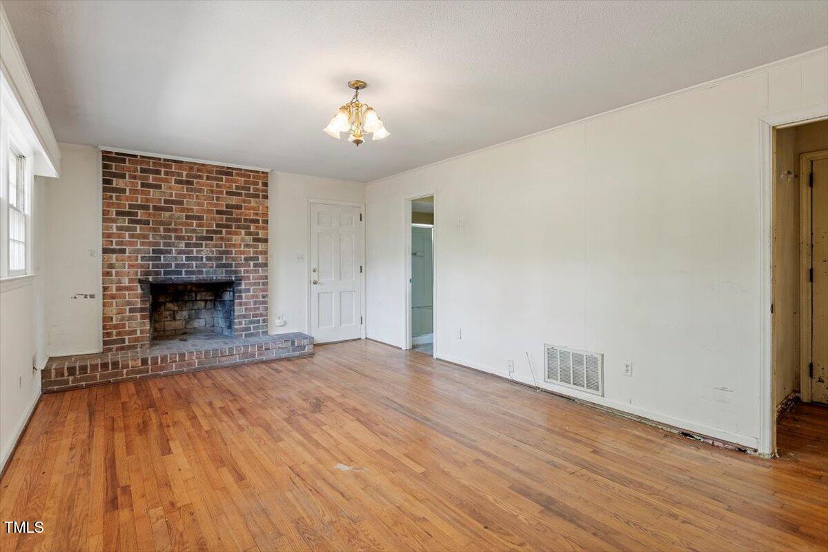 2343 Derby Drive Raleigh, NC 27610 - Photo 11 of 28 a view of empty room with wooden floor and fireplace