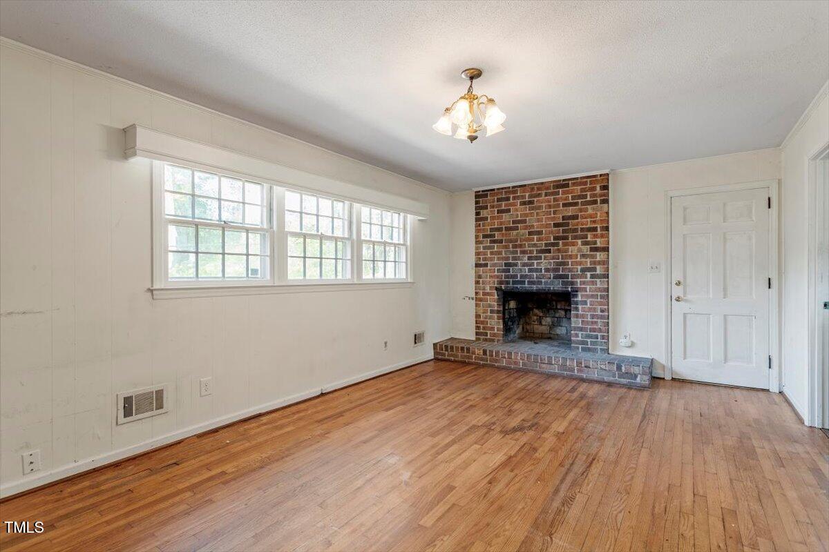 2343 Derby Drive Raleigh, NC 27610 - Photo 12 of 28 an empty room with wooden floor fireplace and windows