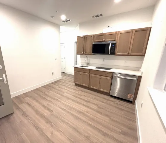 a large kitchen with stainless steel appliances wooden cabinets and a wooden floor