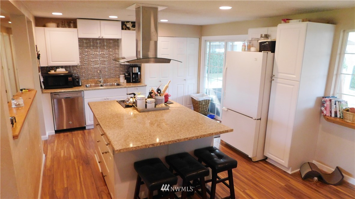 18419 Nutmeg Street Southwest Rochester, WA 98579 - Photo 8 of 24 a kitchen with stainless steel appliances granite countertop a refrigerator a sink a stove and white cabinets with wooden floor