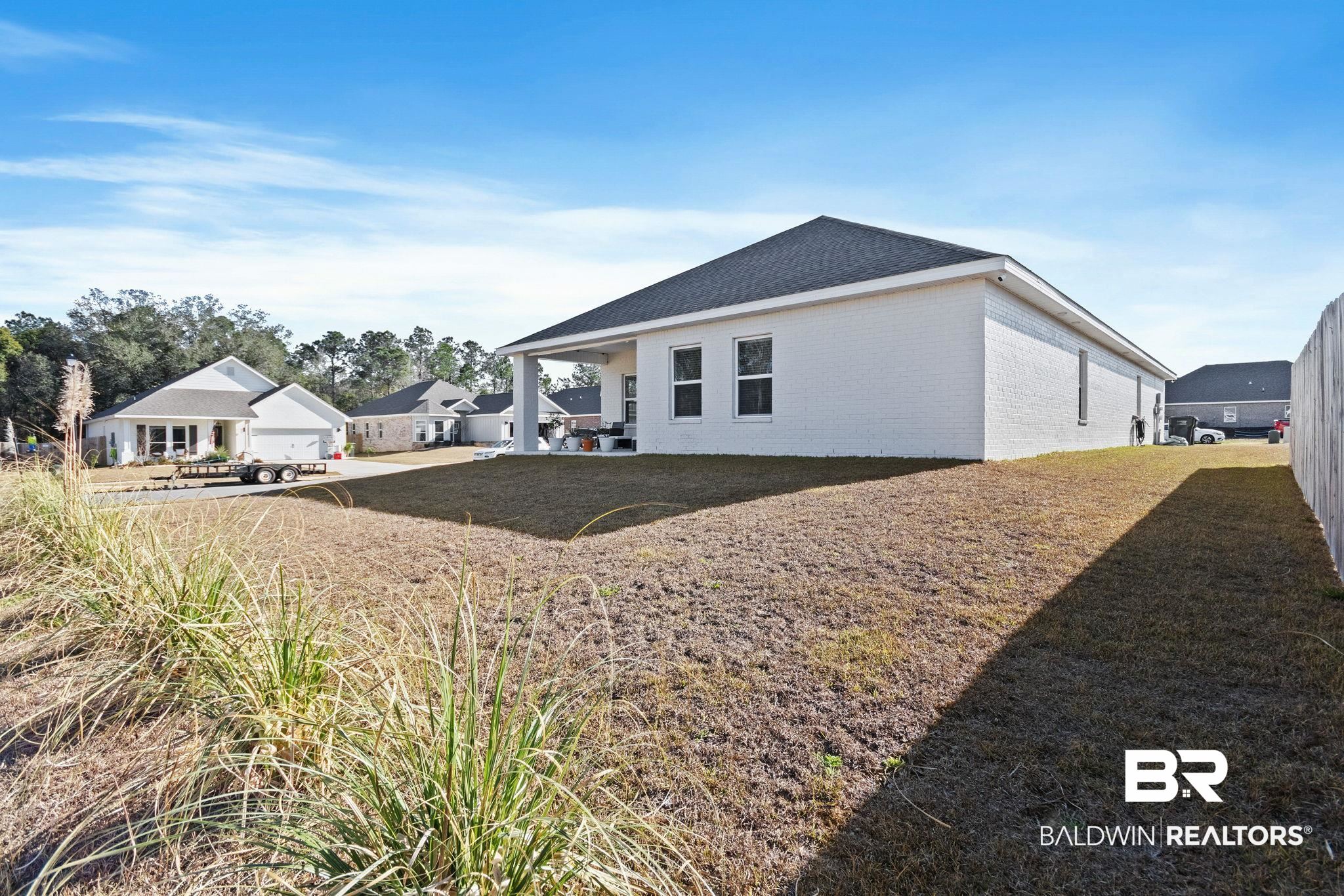 12919 Torrent Road Fairhope, AL 36532 - Photo 48 of 74 Back of property with brick siding, a patio, a lawn, and a shingled roof