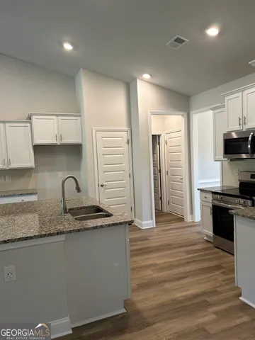 a view of kitchen with kitchen island wooden floors and stainless steel appliances