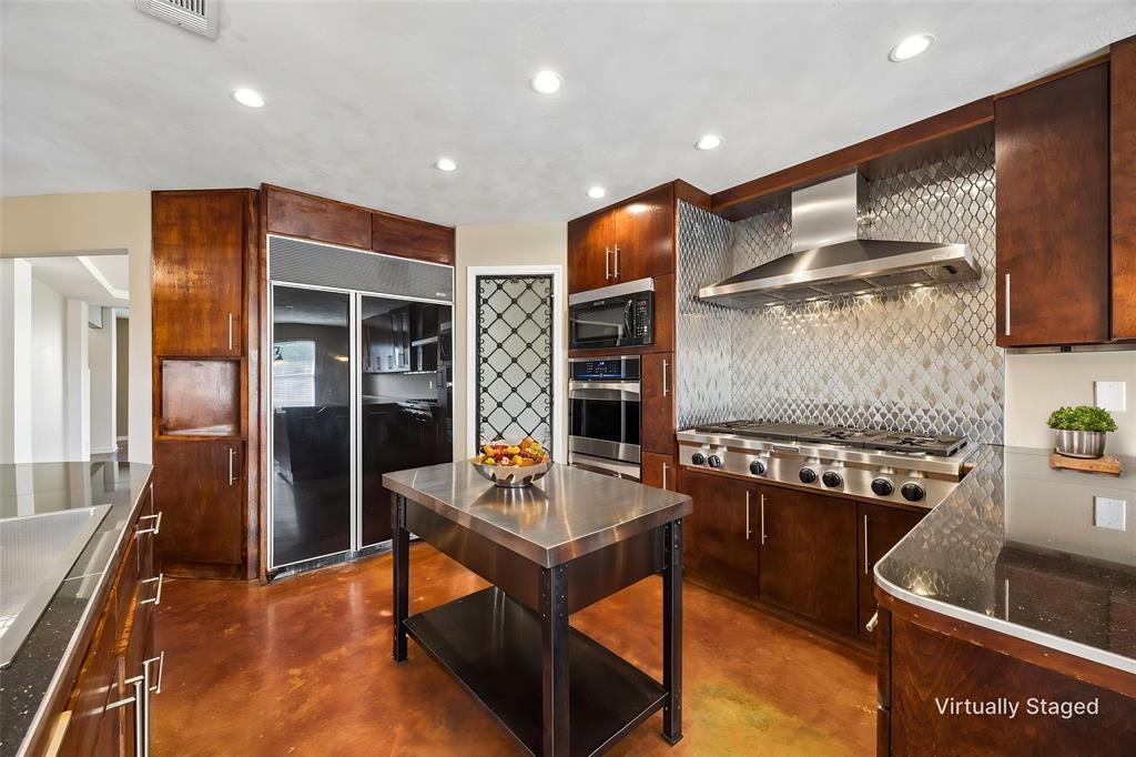 a kitchen with stainless steel appliances granite countertop a sink and a refrigerator