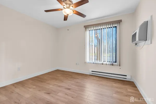 an empty room with wooden floor fan and windows