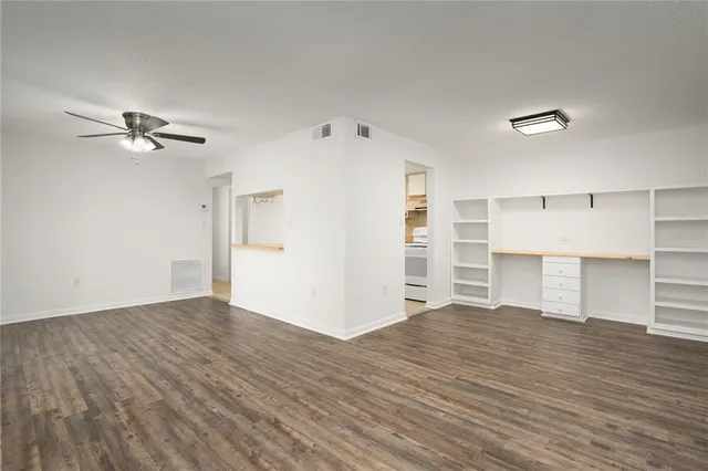 a view of empty room with wooden floor and ceiling fan