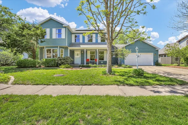 a front view of a house with a yard and green space