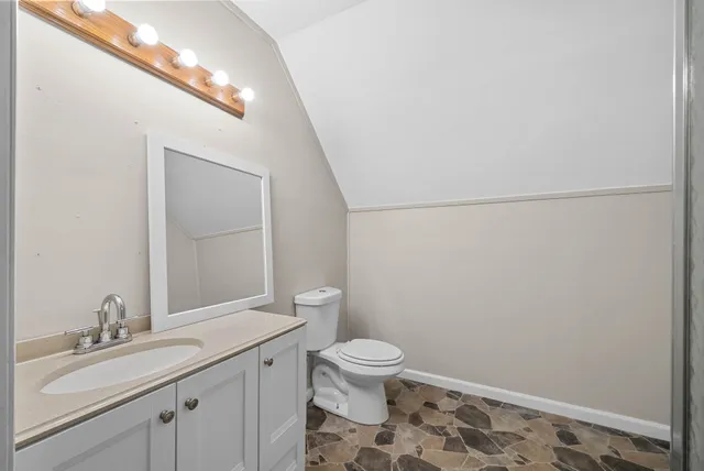 a bathroom with a granite countertop sink mirror vanity and toilet