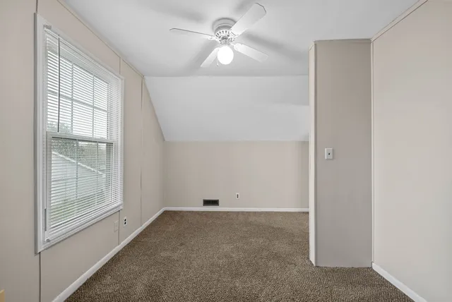 an empty room with windows and fan