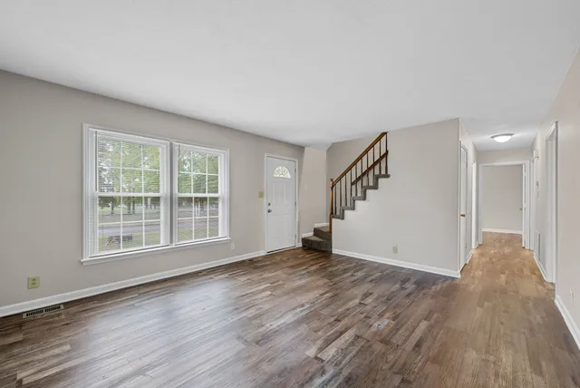 a view of an empty room with wooden floor and a window