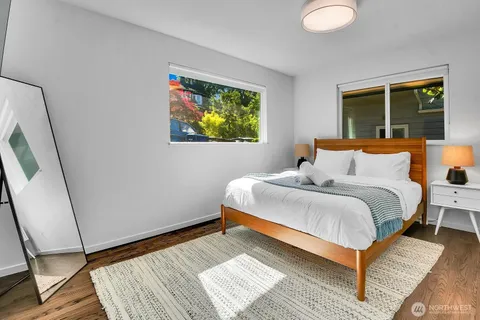 a bedroom with a bed lamp on desk and a window
