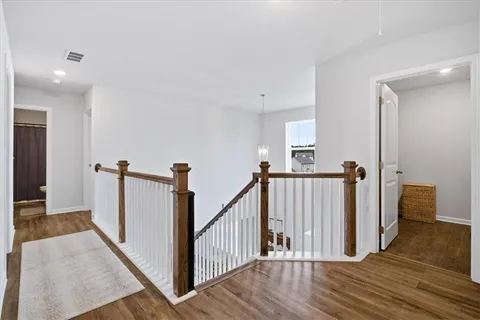 a view of a hallway with wooden floor and staircase