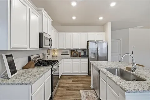 a kitchen with granite countertop a sink stove and refrigerator