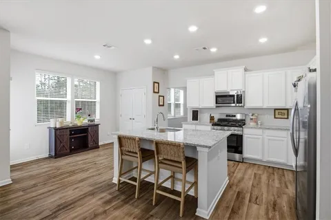 a kitchen with stainless steel appliances a stove a sink dishwasher a refrigerator with wooden cabinets and wooden floor