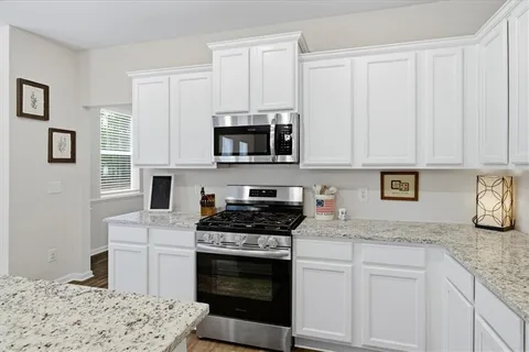 a kitchen with granite countertop a stove a sink and a microwave