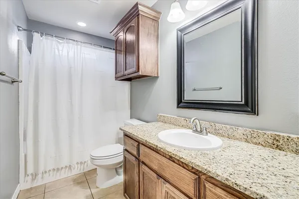 a bathroom with a granite countertop sink toilet and mirror