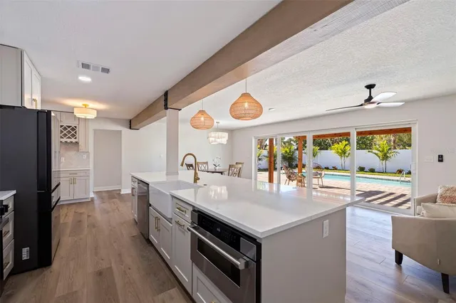 a large kitchen with stainless steel appliances a large window and a refrigerator
