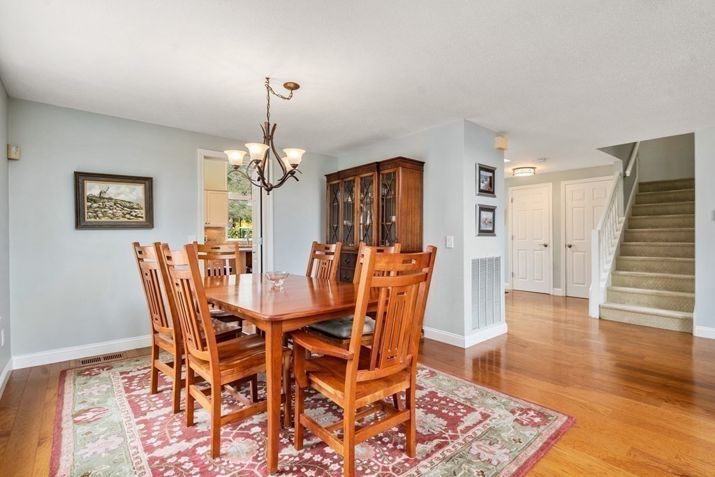 1 Pickwick Way, Unit 1 Wayland, MA 01778 - Photo 11 of 32 a dining room with furniture wooden floor a rug and a chandelier