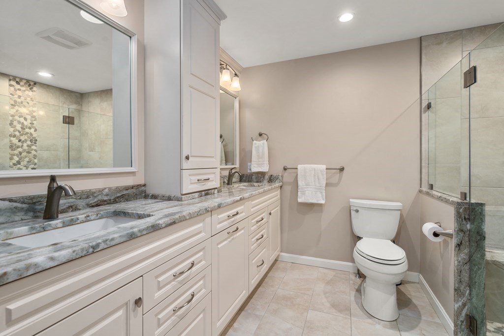 1 Pickwick Way, Unit 1 Wayland, MA 01778 - Photo 14 of 32 a bathroom with a granite countertop toilet a sink and a mirror