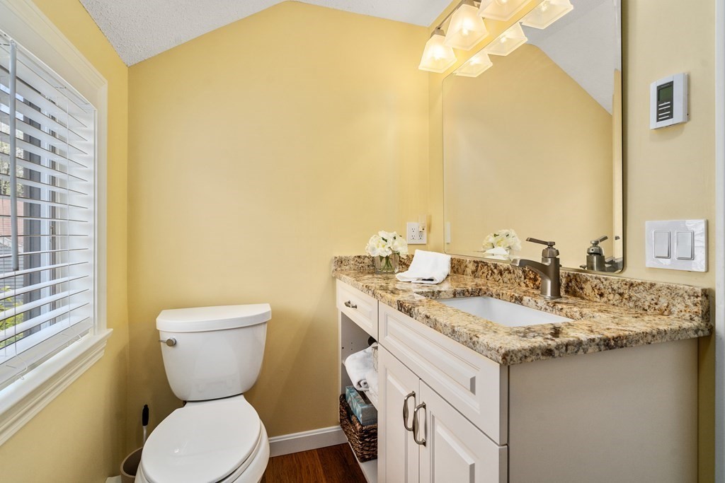 1 Pickwick Way, Unit 1 Wayland, MA 01778 - Photo 17 of 32 a bathroom with a granite countertop toilet sink and mirror