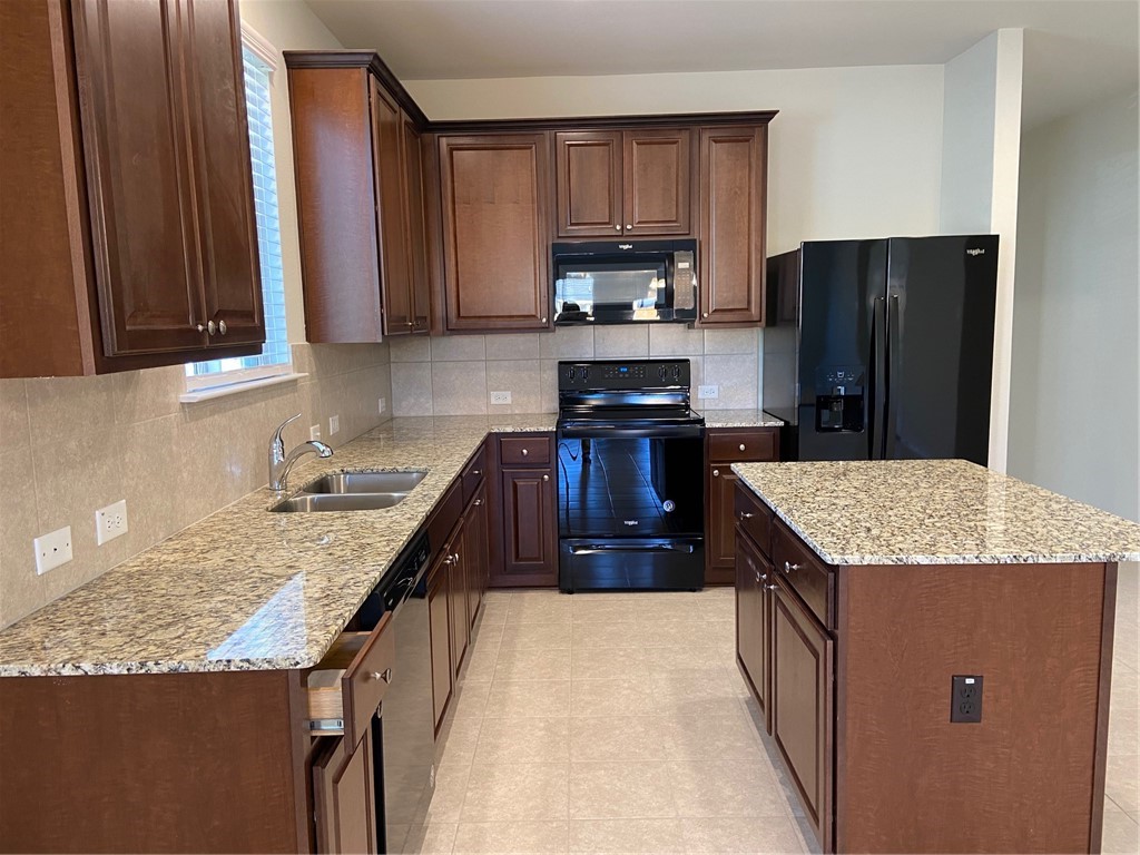 200 Kildeer Pass Jarrell, TX 76537 - Photo 9 of 27 a kitchen with stainless steel appliances granite countertop wooden cabinets a refrigerator and a sink