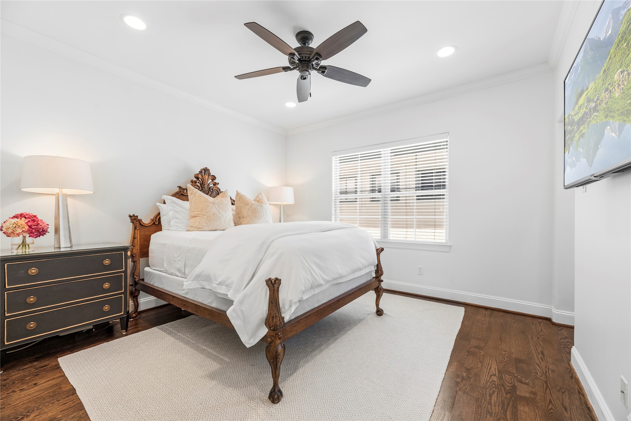 1537 Haddon Street Houston, TX 77006 - Photo 24 of 48 Second bedroom features hardwood floors, a ceiling fan, and a large window for natural light, creating a cozy and inviting atmosphere. Note the en-suite bathroom entry to the right side of this picture.