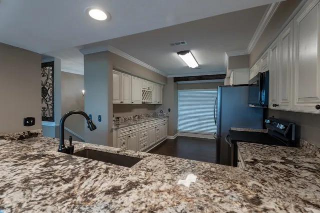 a kitchen with stainless steel appliances kitchen island granite countertop a stove a sink and a refrigerator