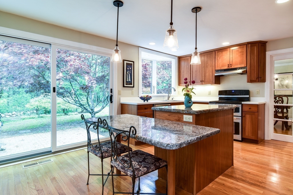 114 Hunters Ridge Road Concord, MA 01742 - Photo 12 of 38 a kitchen with granite countertop a stove a sink a kitchen island a table and chairs in it