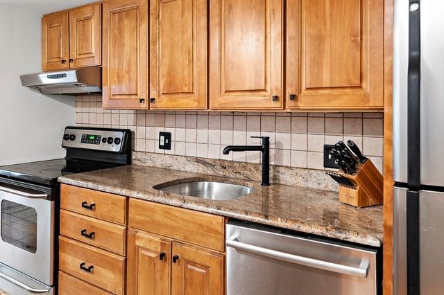 a kitchen with granite countertop a sink a stove and cabinets