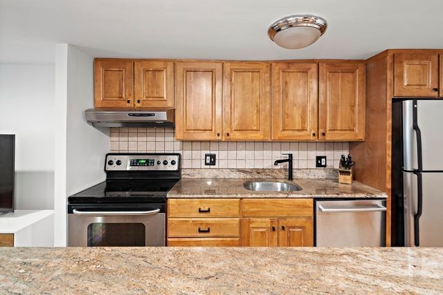 a kitchen with stainless steel appliances granite countertop a stove a sink and a refrigerator