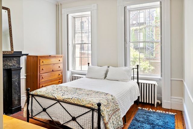 a bedroom with a bed and a dresser next to a window