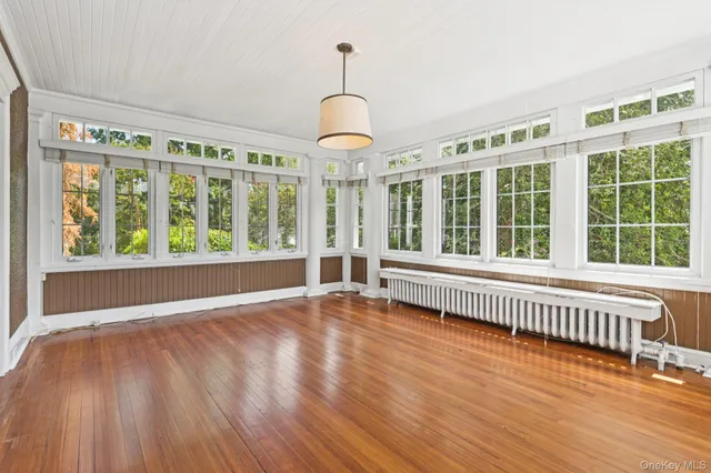 a view of an empty room with wooden floor and windows