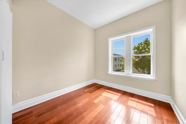 an empty room with wooden floor and a window