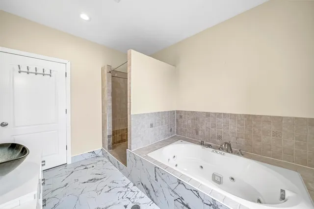 a bathroom with a tub a sink and a large mirror