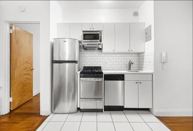 a kitchen with white cabinets a refrigerator and a stove